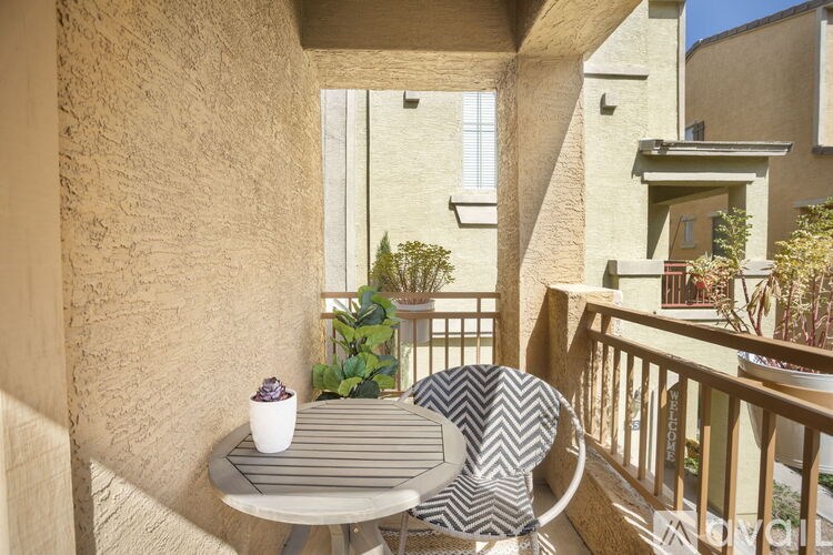 A table with a striped cushion and a cup on it is on a balcony.