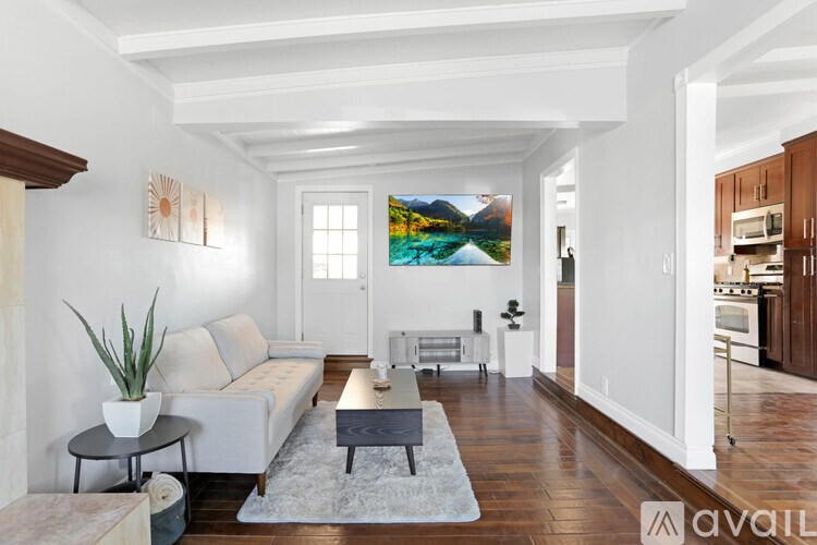 A living room with a white couch and a painting on the wall.
