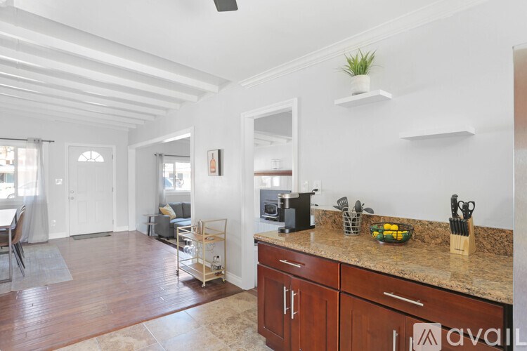 A kitchen with wooden floors and a counter with a bowl of fruit on it.