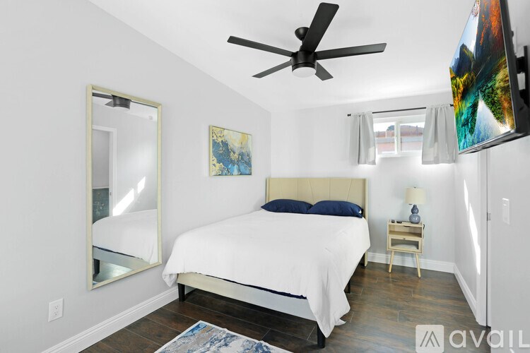 A bedroom with a large bed and a ceiling fan.