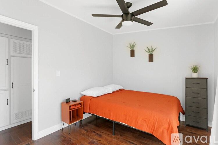 A bedroom with a bed, nightstand, and a ceiling fan.