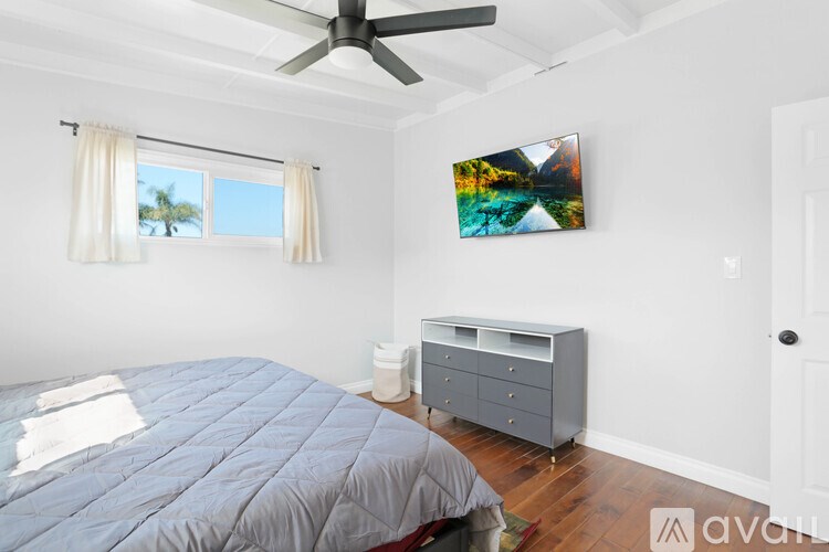 A bedroom with a bed, dresser, and a ceiling fan.