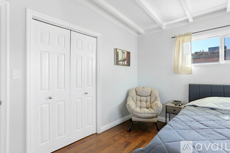 A bedroom with a bed, chair, and a window.