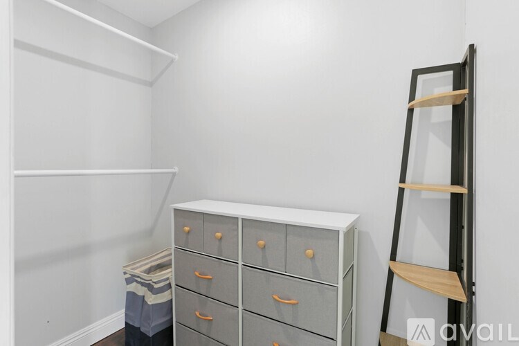 A white shelving unit with a black ladder stands next to a grey filing cabinet with orange handles.