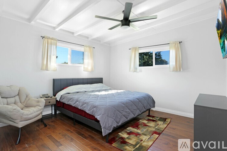 A bedroom with a bed, chair, and ceiling fan.