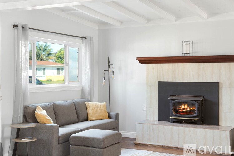 A living room with a grey couch and a fireplace.