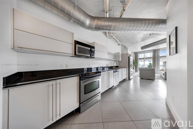 A modern kitchen with white cabinets and black countertops.