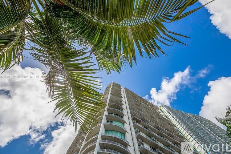A tall building with a clear blue sky and palm trees in the foreground.