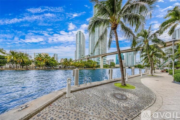A walkway with a palm tree and a body of water in the background.