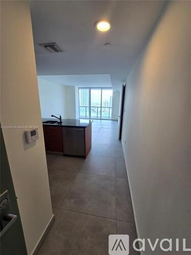 A hallway with a green door and a trash can.