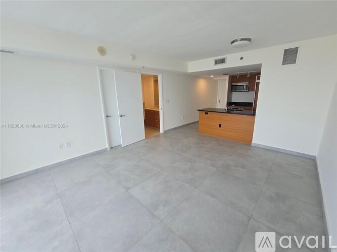 A spacious living room with a kitchen in the background.