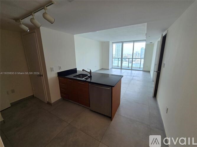 A spacious kitchen with a black countertop and a large window overlooking the city.
