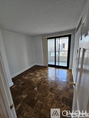 A room with a brown floor and a sliding glass door.