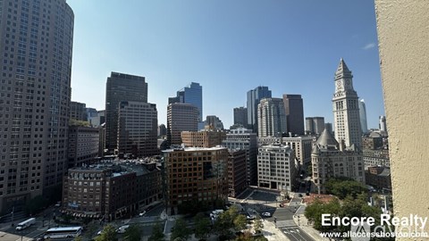 A cityscape with a mix of modern and older buildings, with a clear blue sky above.