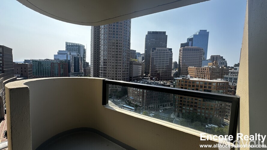 A cityscape viewed from a balcony with a white railing.