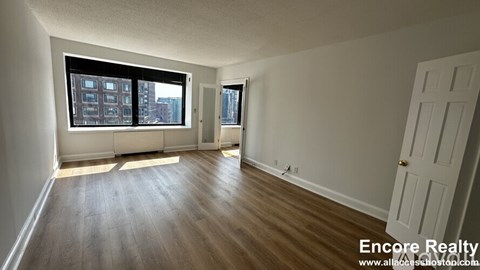 A room with wooden floors and a large window overlooking a cityscape.