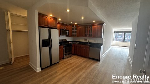 A kitchen with wooden cabinets and a stainless steel refrigerator.