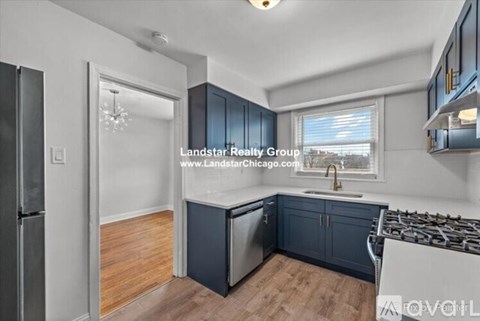 A kitchen with dark blue cabinets and a wooden floor.