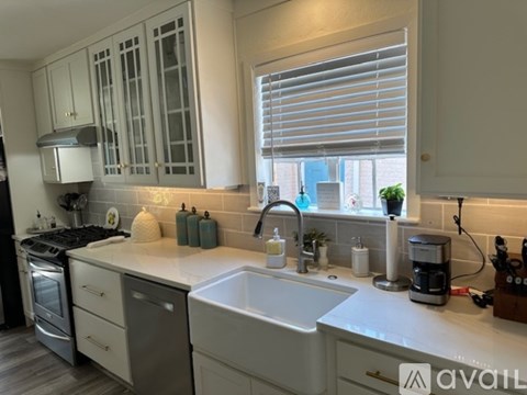 A kitchen with a stove, sink, and window.