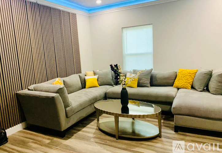 A living room with a grey sofa, a glass coffee table, and a striped wallpaper.
