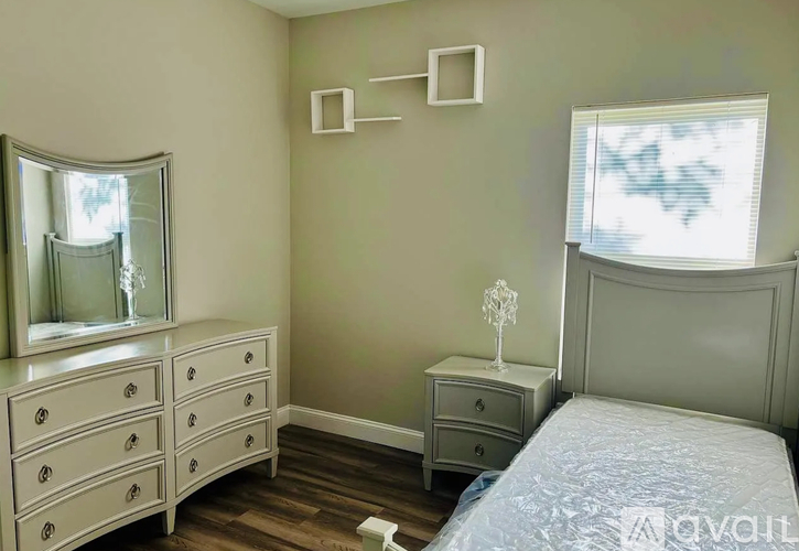 A bedroom with a bed, dresser, and mirror.