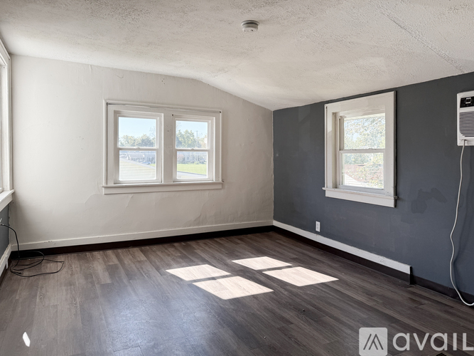 A room with two windows and a wooden floor.