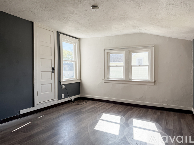 A room with a door, two windows, and a wooden floor.