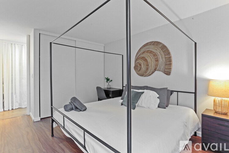 A bed with a white comforter and a large shell on the wall.