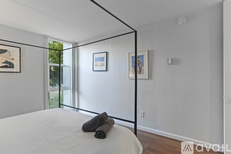 A bedroom with a white bed and a window with a view of trees.