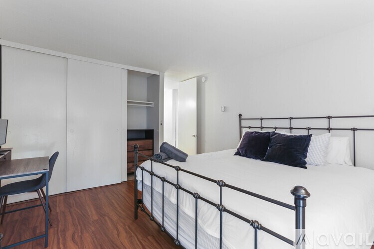 A bedroom with a bed, chair, and desk.