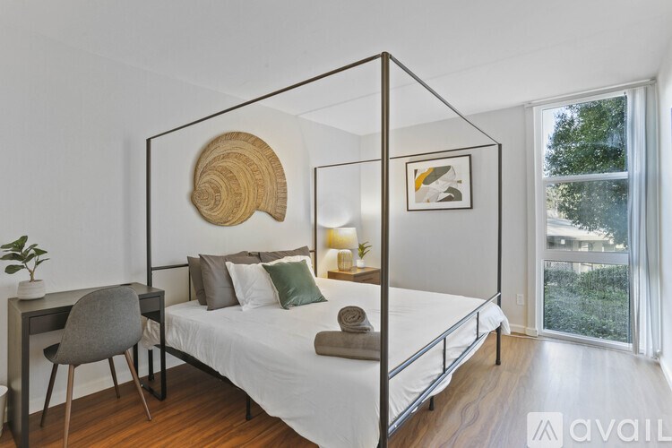 A bedroom with a four poster bed, a chair, and a plant.