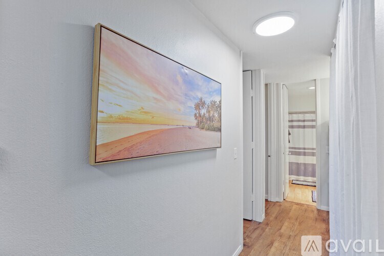 A painting of a sunset scene is hanging on a white wall in a room.