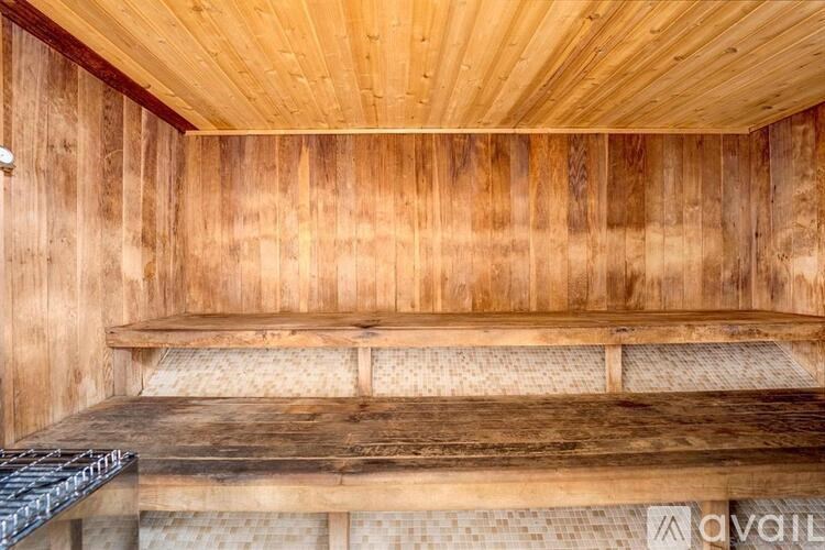 A wooden room with a bench and a grill on the floor.