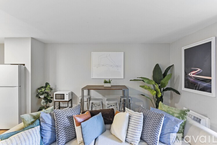 A living room with a couch, pillows, and a fridge.