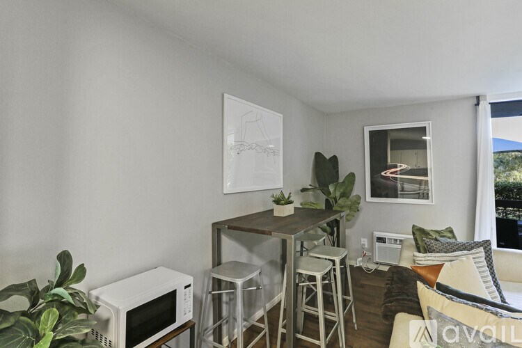 A white room with a microwave, a table with chairs, and a potted plant.