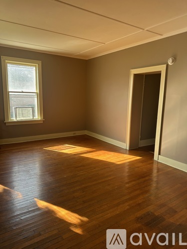 A room with wooden floors and a window letting in sunlight.