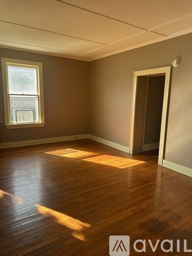 A room with wooden floors and a window letting in sunlight.