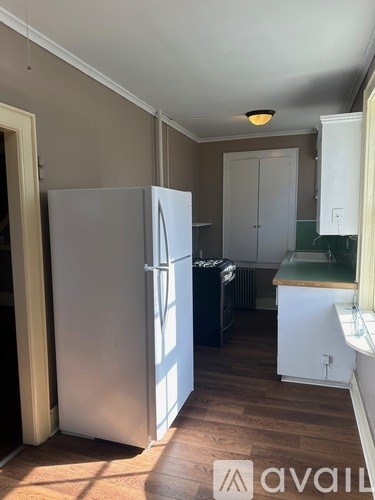 A kitchen with a white refrigerator and wooden floors.