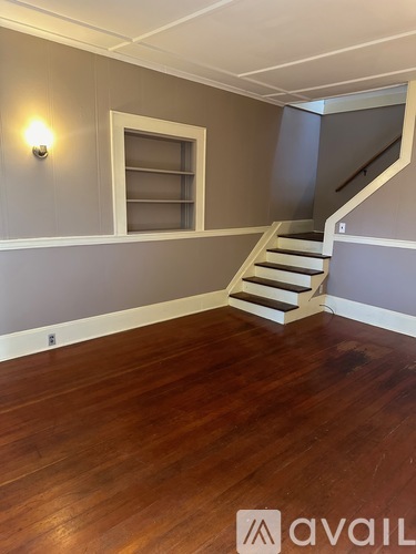 A room with wooden floors and a staircase leading to another room.