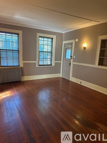 A room with wooden floors and a window with blinds.