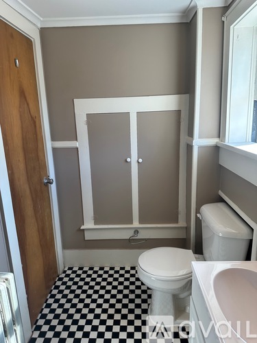 A bathroom with a toilet, sink and a checkered floor.