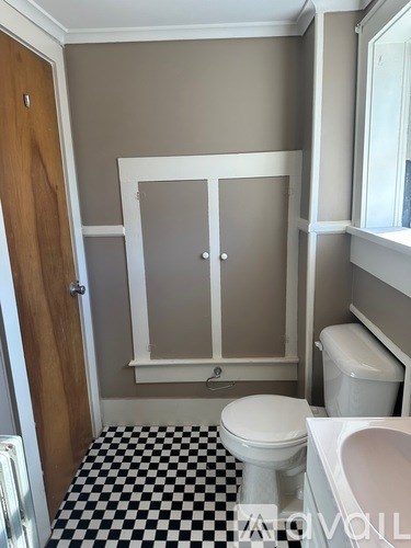 A bathroom with a toilet, sink and a checkered floor.