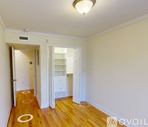 A room with wooden floors and white walls, with a doorway leading to another room.