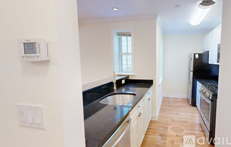 A kitchen with a stainless steel sink and black countertops.