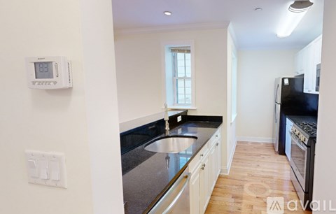 A kitchen with a stainless steel sink and black countertops.