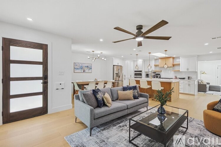A modern living room with a grey couch and a glass coffee table.