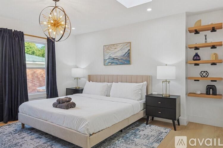 A bedroom with a large bed, a chandelier, and a painting on the wall.