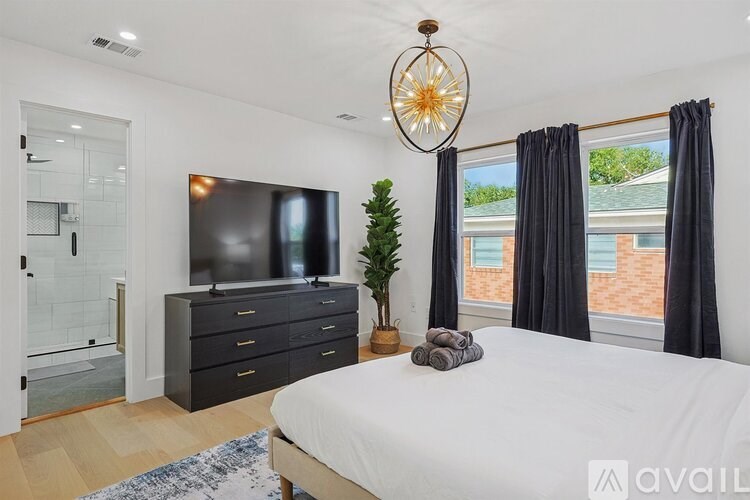 A bedroom with a large bed, a flat-screen TV, and a plant.