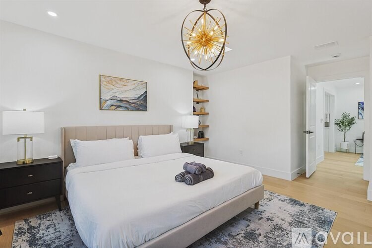 A bedroom with a large bed, a nightstand with a lamp, and a painting on the wall.