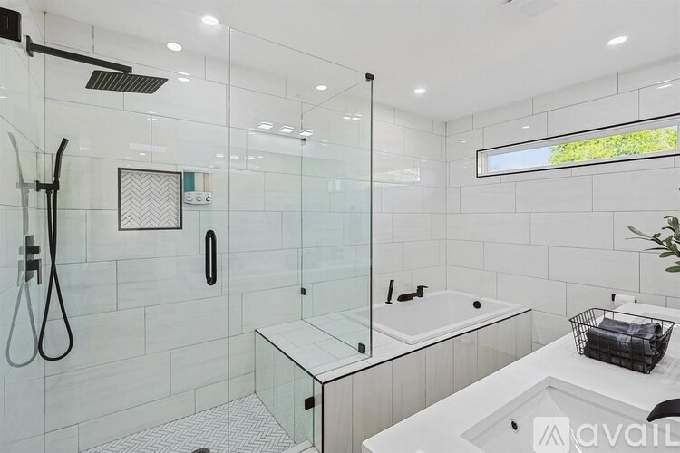 A modern bathroom with a glass shower area and a white sink.